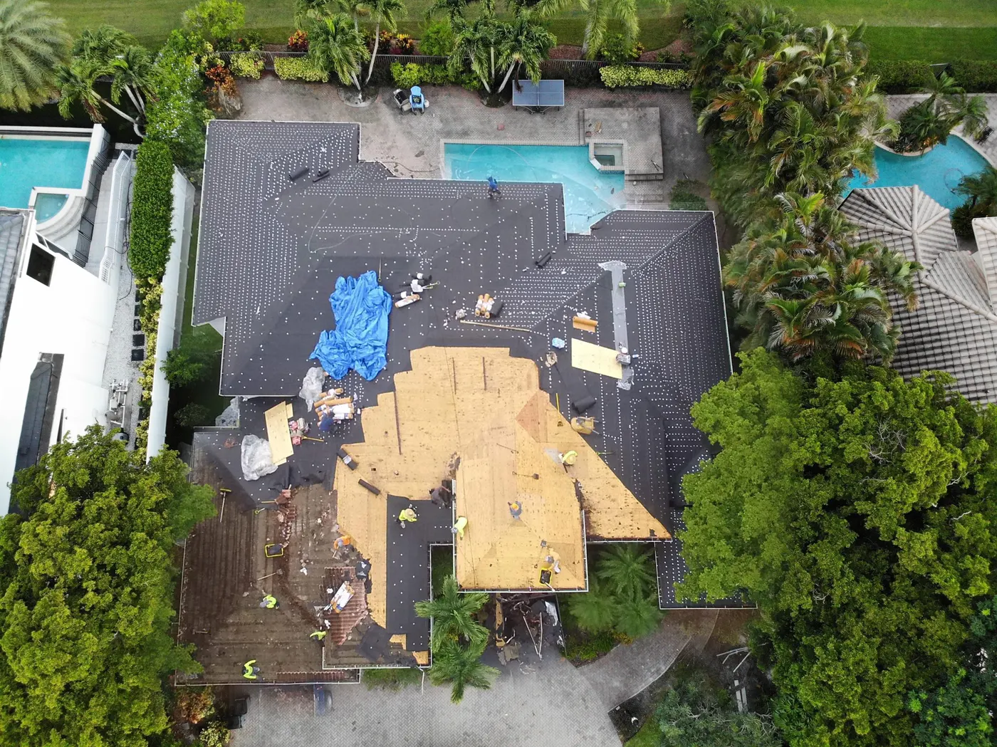 Aerial view of a South Florida home mid-tear-off with exposed decking and underlayment